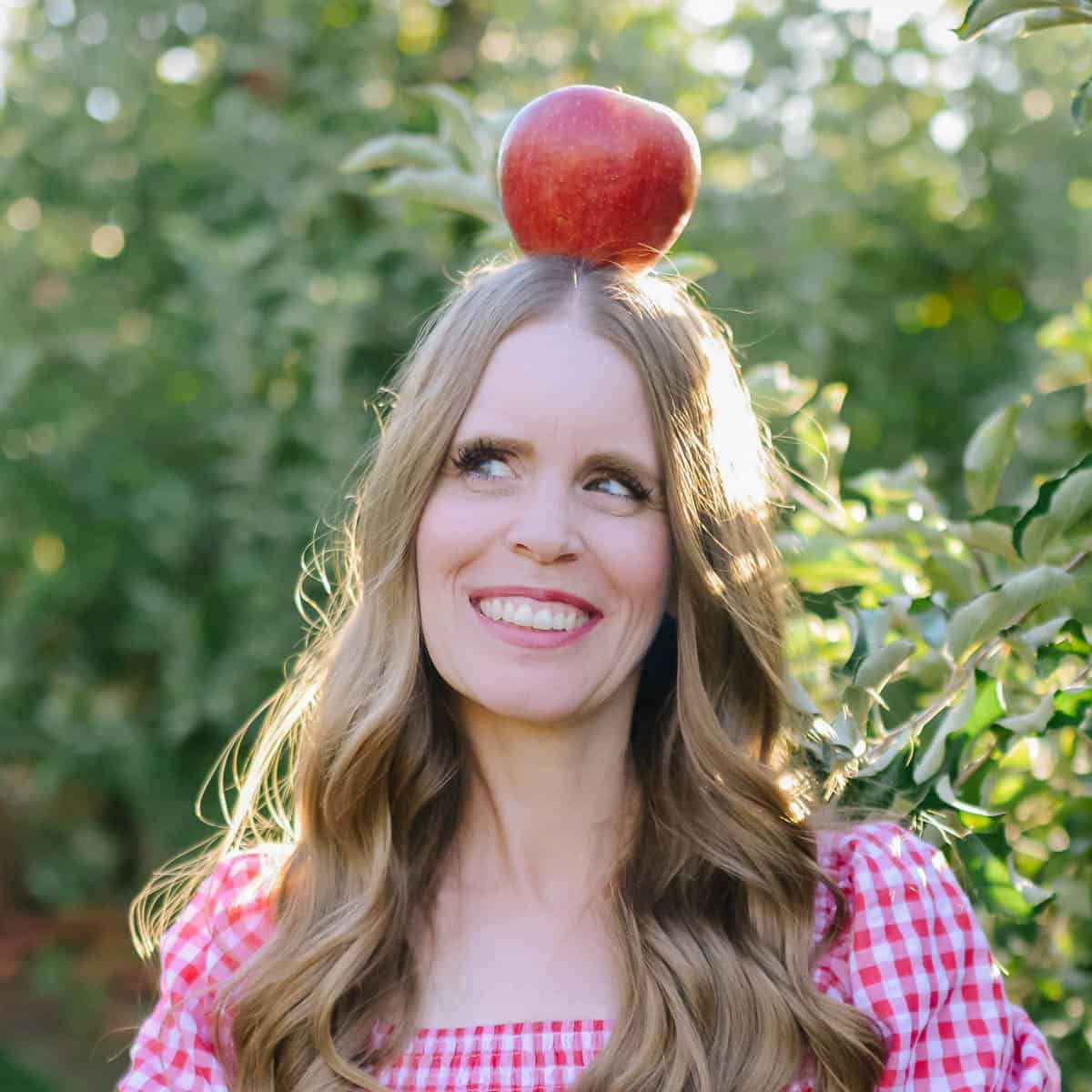 Janice balancing an apple on her head in an orchard for Ruby Apple Kitchen