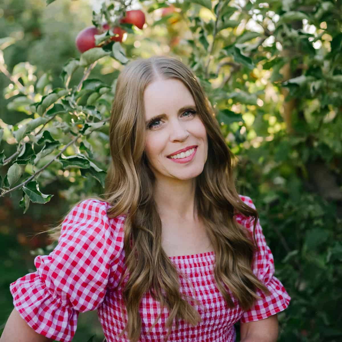Janice smiling in an apple orchard for Ruby Apple Kitchen
