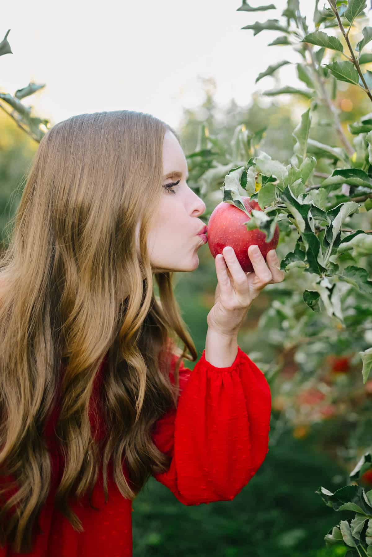 Janice kissing an apple in an orchard for Ruby Apple Kitchen
