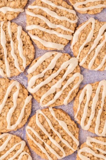 Overhead view of chewy maple oatmeal cookies drizzled with cream-colored glaze.