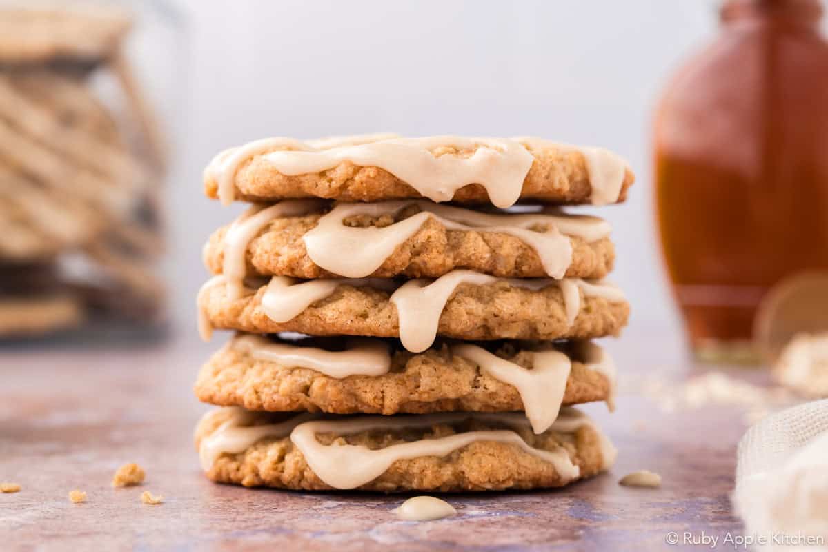 Stack of maple oatmeal cookies with cream-colored glaze drizzled over the tops.