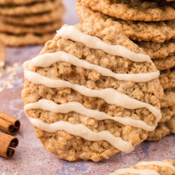 Close-up of a maple-glazed oatmeal cookie leaning against a stack of chewy cookies.