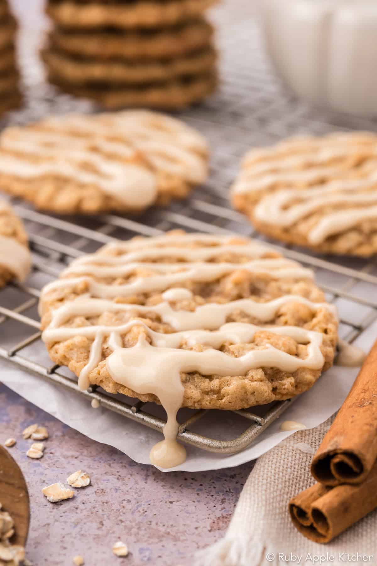Close-up of maple glaze dripping off the edge of an oatmeal cookie on a cooling rack.