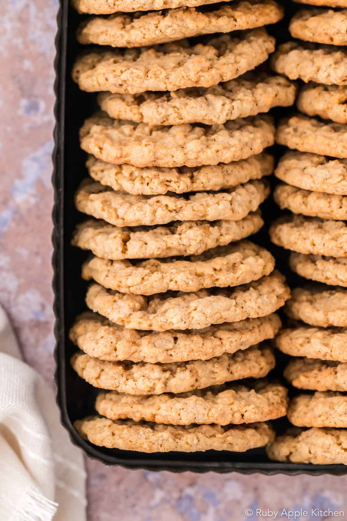 Two rows of maple oatmeal cookies standing on their edges inside a rectangular metal tin.